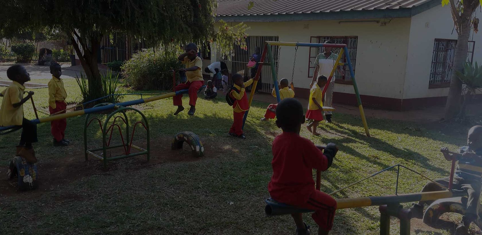 Children playing on the swings and see-saw at the Mumvuri Project community centre in Banket, Zimbabwe